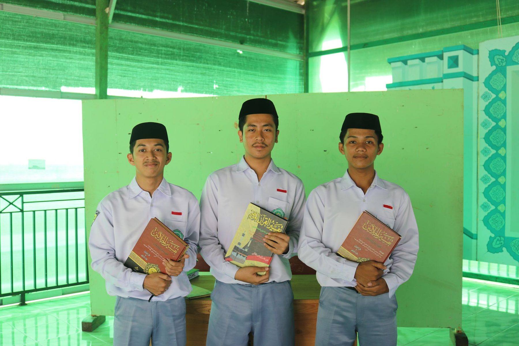 Tiga siswa SMA berseragam putih-abu-abu memegang buku pelajaran