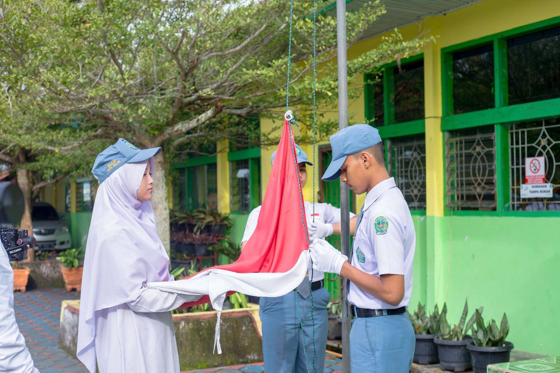 Siswa SMA berseragam putih-abu-abu mengibarkan bendera saat upacara
